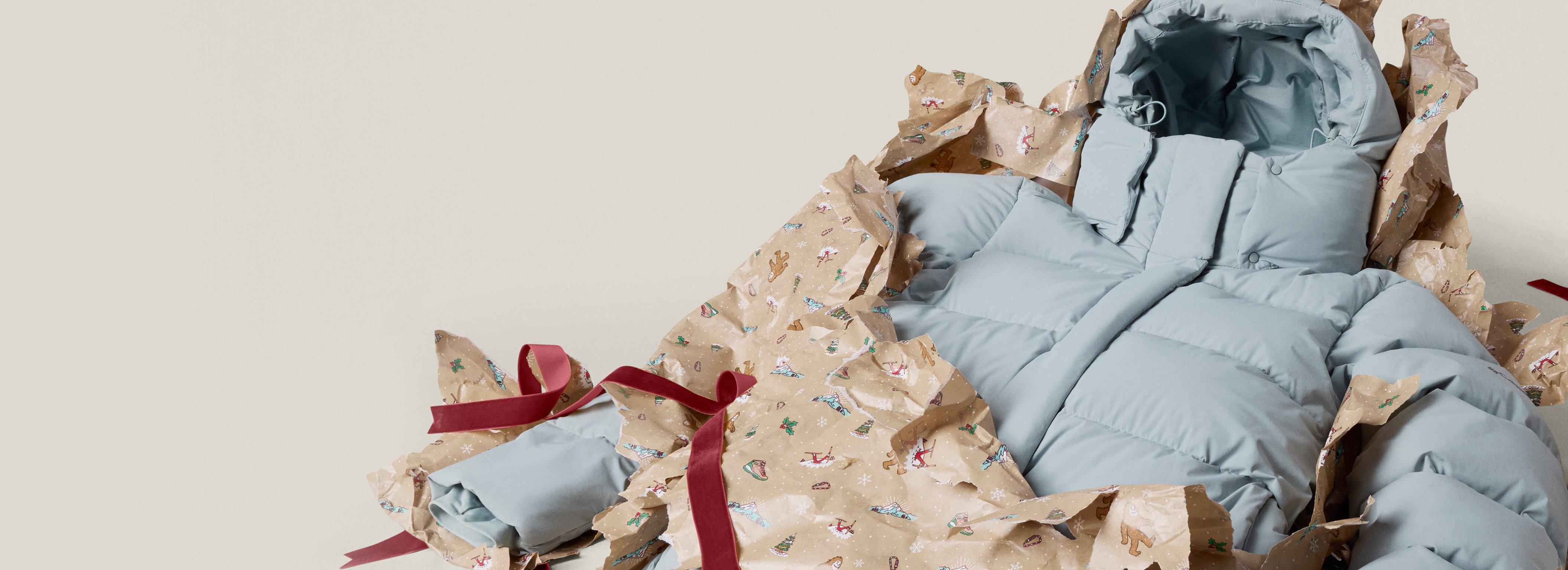 A blue puffer jacket busting out of turn up wrapping paper.