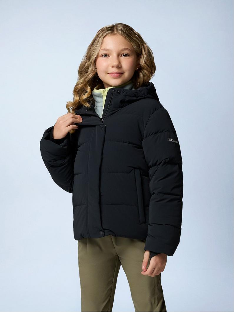 Child wearing black puffer jacket with hood over olive pants, smiling at camera.