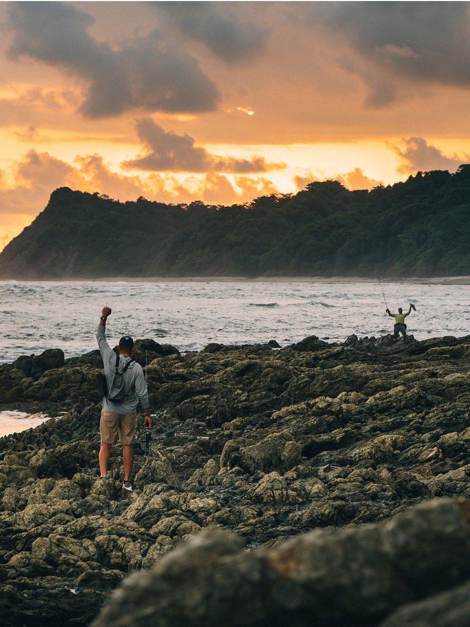Two anglers celebrating a catch as the sun sets.