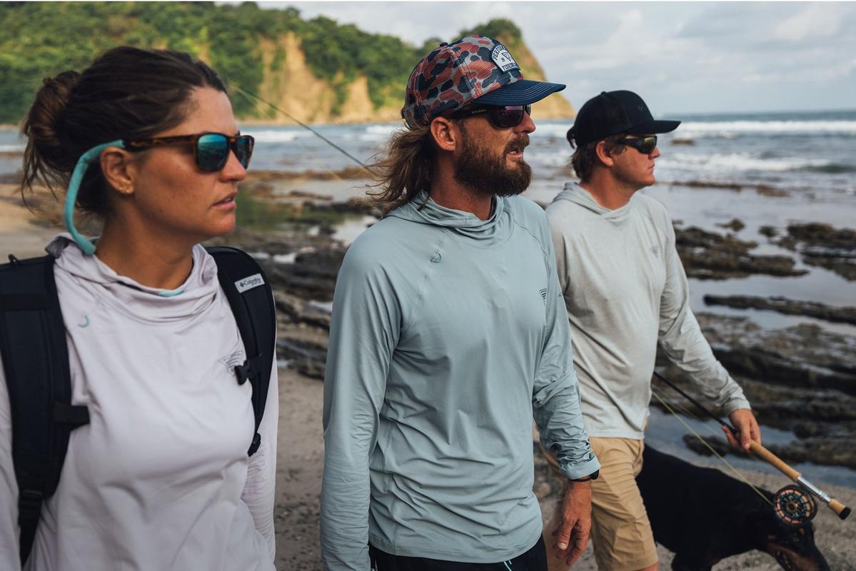 Three anglers walking on a beach.