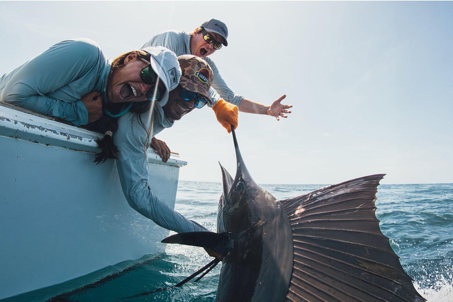 Anglers smiling and holding up a big fish.