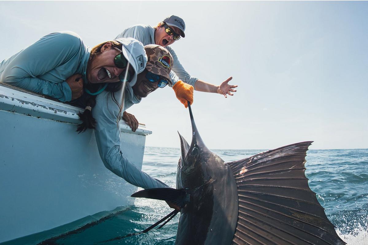 Anglers smiling and holding up a big fish.