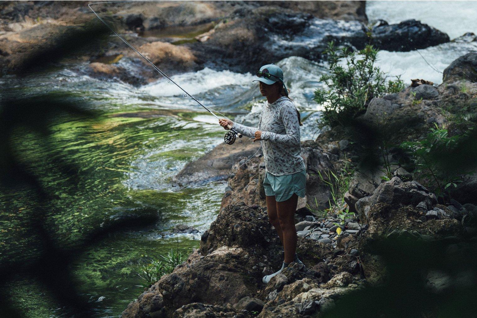 Angler standing on a rock, casting her line.