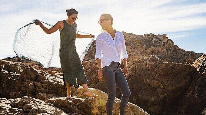Two women hike along a rocky trail.