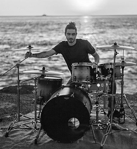 A man plays the drums on a coastal bluff in Portugal.