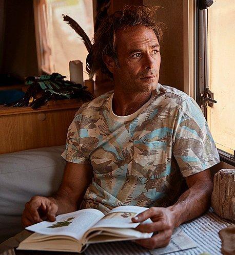 A man reads a book in a brightly lit dining nook.