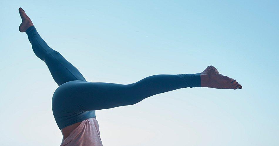 A woman holds a strong yoga pose in an open space.