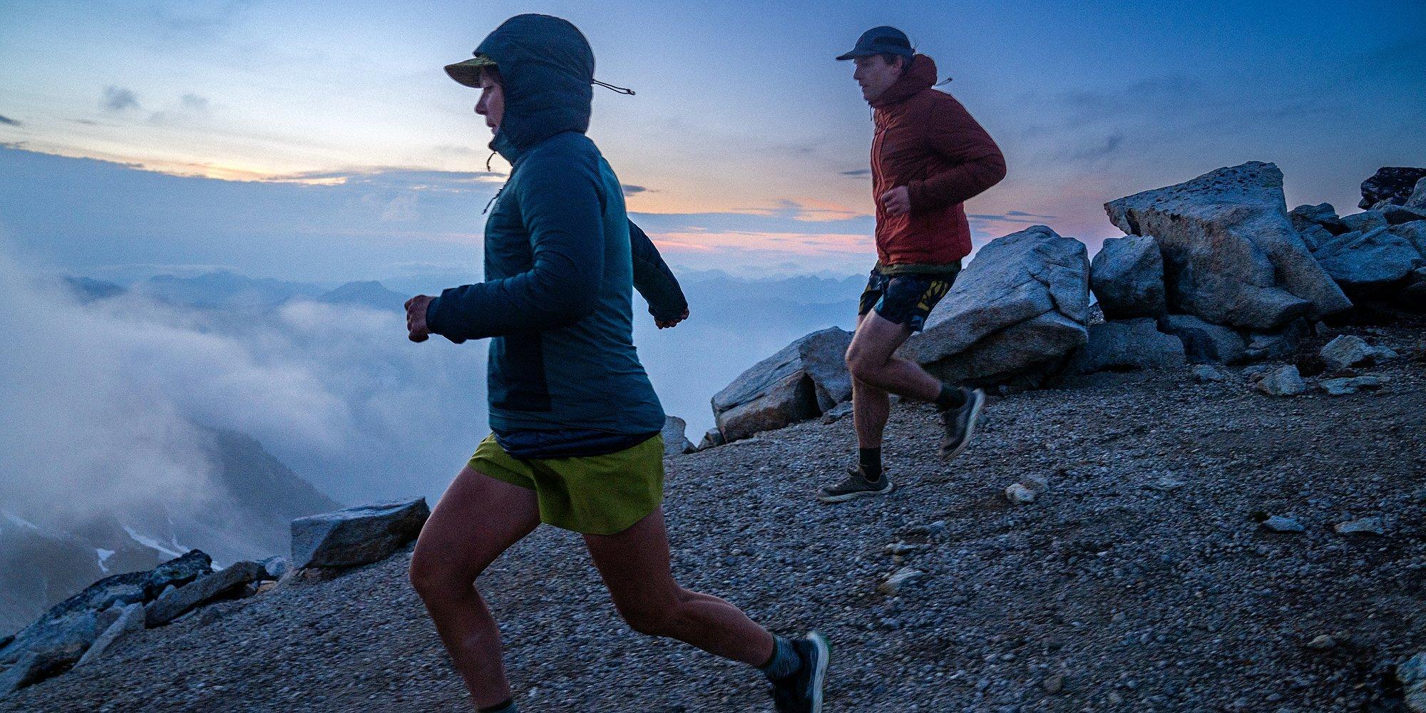 Two runners trail running in the Kor AirShell Hybrid above the colds at sunrise.