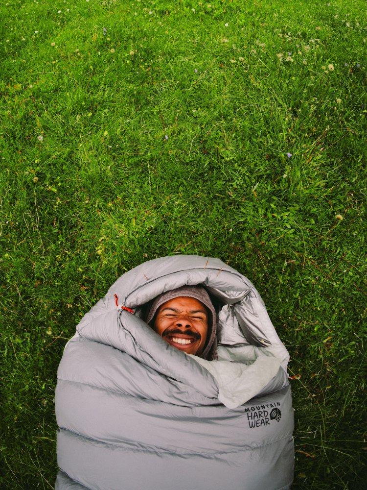 A man with closed eyes and a spritely grin lays on grass in a Ghoul™ 20°F/-7°C