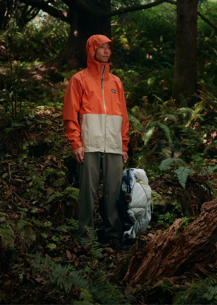Person in a rain shell in a leafy forest.