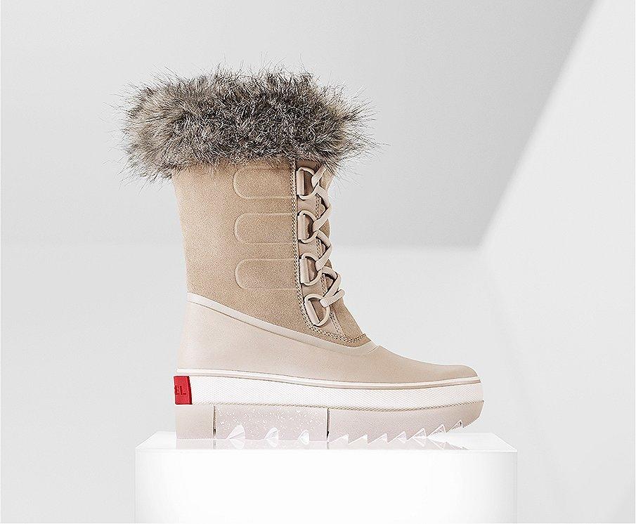 A profile view of a tan Joan NEXT boot on white background