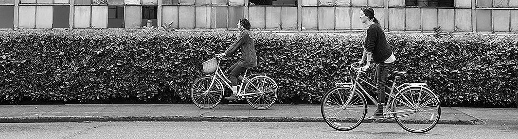 Two women riding a bike around a city while wearing SORELs