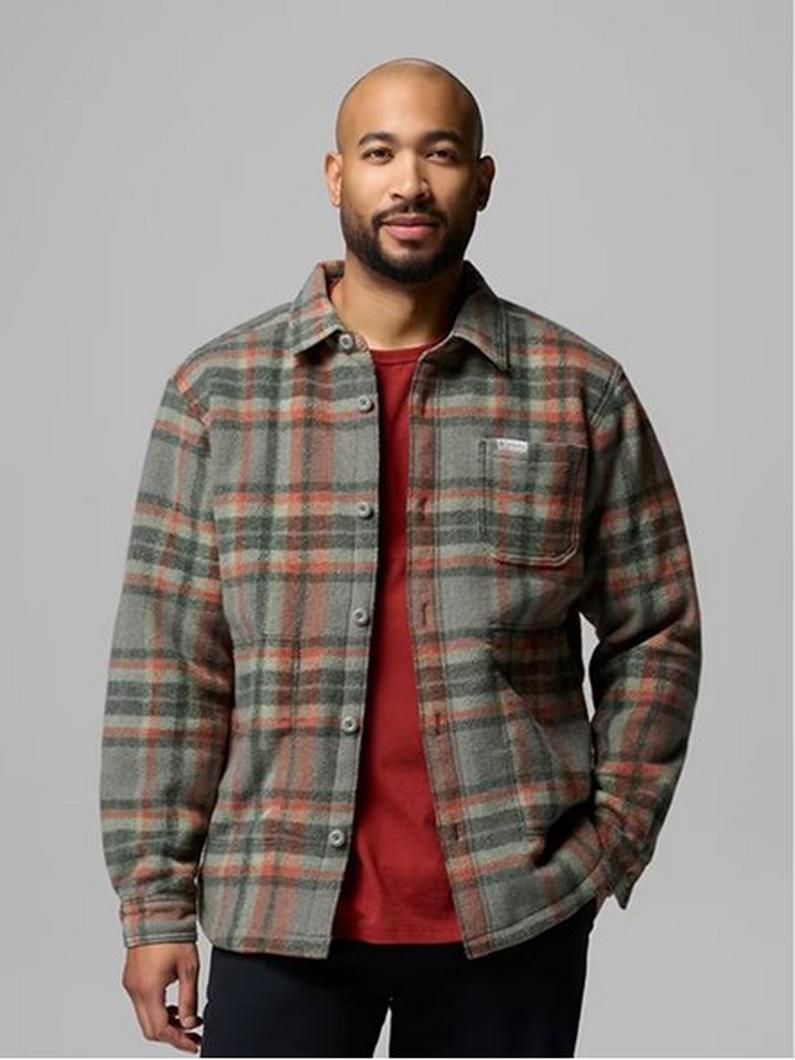 Man wearing gray, orange, and green plaid flannel shirt jacket over red t-shirt.
