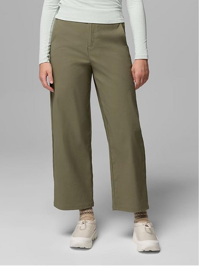 Woman wearing olive green wide-leg pants paired with a white long-sleeve top and cream sneakers.