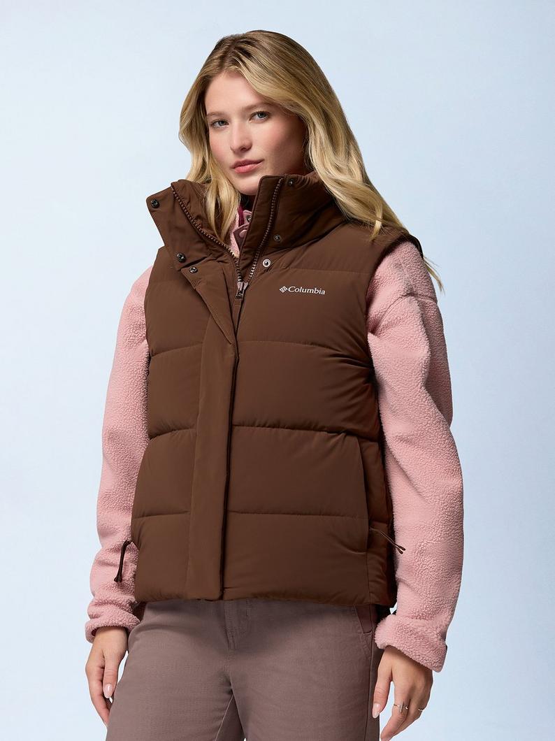 Woman wearing brown puffer vest over pink fleece jacket and gray pants.