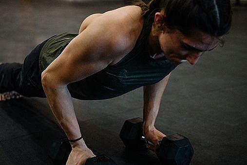 Kyra doing push-ups holding on to weights