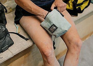 Black and white image of Kyra Condie bouldering, reaching up for her next move.