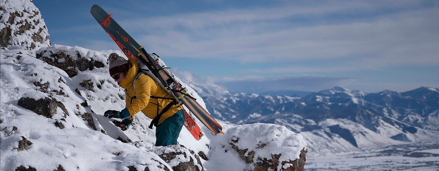 A backcountry skiier climbing some rock to get to the ultimate launching point
