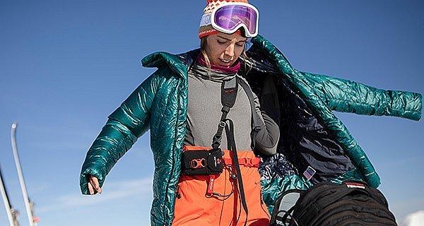 Skiier warming up, pulling on her Women's Phantom™ Down Parkaover.