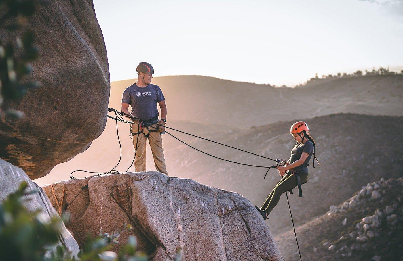 An Outdoor Outreach instructor teaching a young girl how to rappel.
