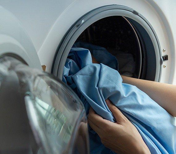 An image of a person putting clothes into a washing machine.